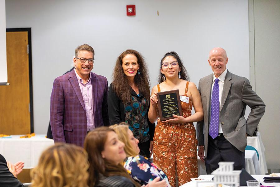 The Merrion Scholar of the Year, Analea Castro (holding the plaque), is pictured with T. Greg Merrion on left, President Dr. Toni Hopper Pendergrass and Board of Trustees member John Thompson.